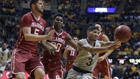 West Virginia guard James Bolden passes the ball as Oklahoma forward Matt Freeman and guard Kameron Mc Gusty defend during the second half of an NCAA college basketball game Saturday Jan. 6 2018 in Morgantown