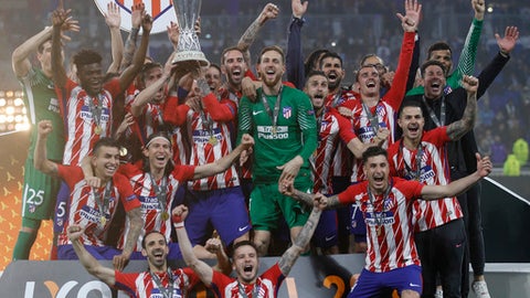 Atletico players with head coach Diego Simeone far right in black celebrate with the trophy after winning the Europa League Final soccer match between Marseille and Atletico Madrid at the Stade de Lyon in Decines outside Lyon France Wednesday May 16