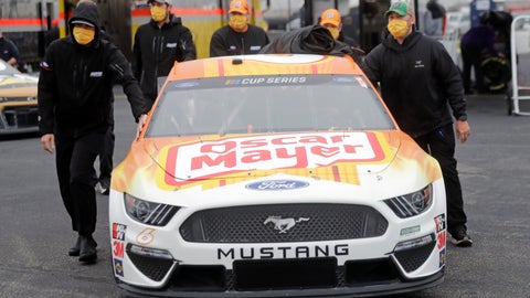Crew members push the car of driver Ryan Newman as they wear masks as required for safety measures due to the coronavirus pandemic before the Toyota 500 NASCAR Cup Series auto race Wednesday